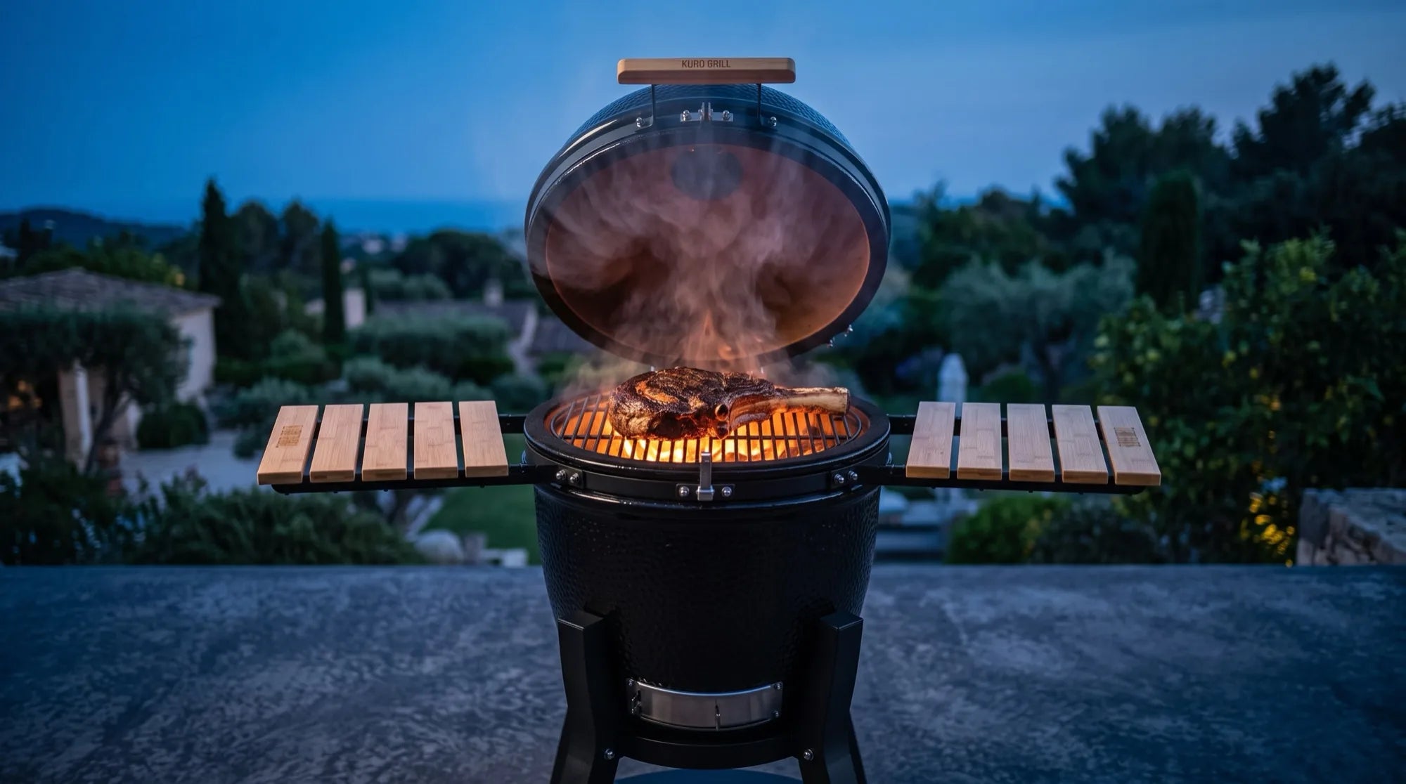 Kamado Kuro Grill abierto, sellando un tomahawk al atardecer