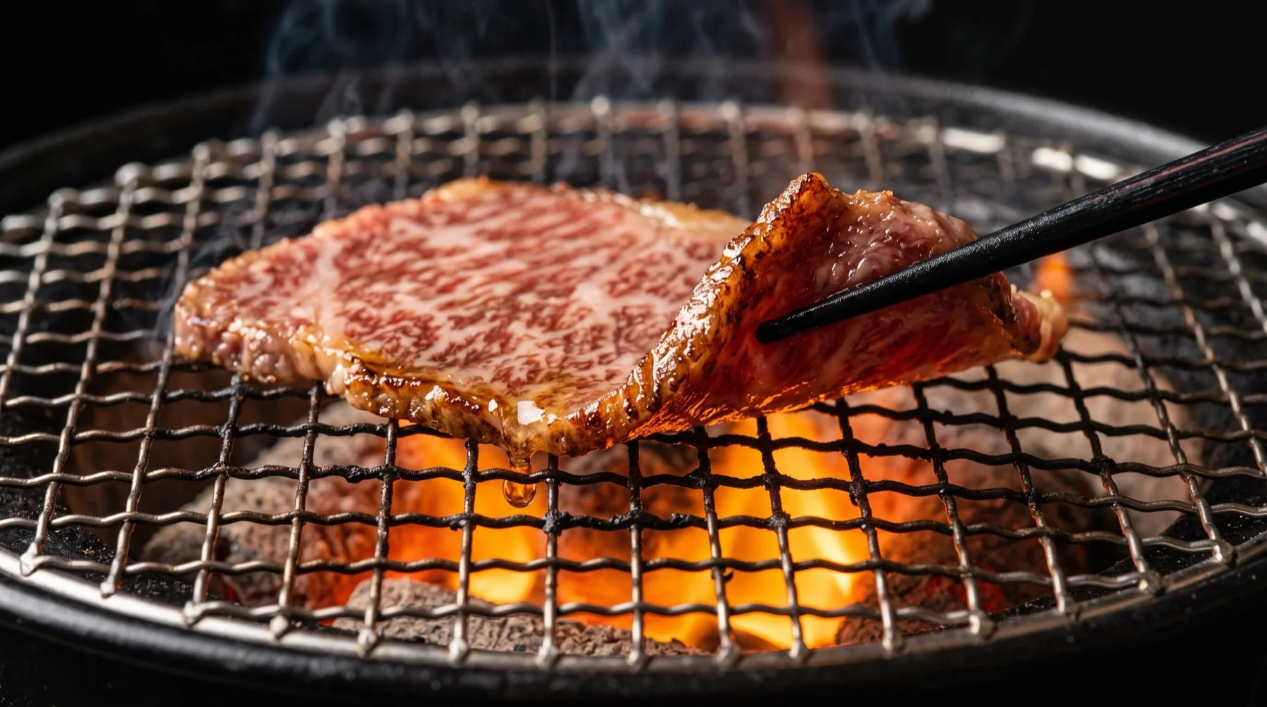 Lámina de wagyu A5 sobre la malla del asador, con la brasa debajo